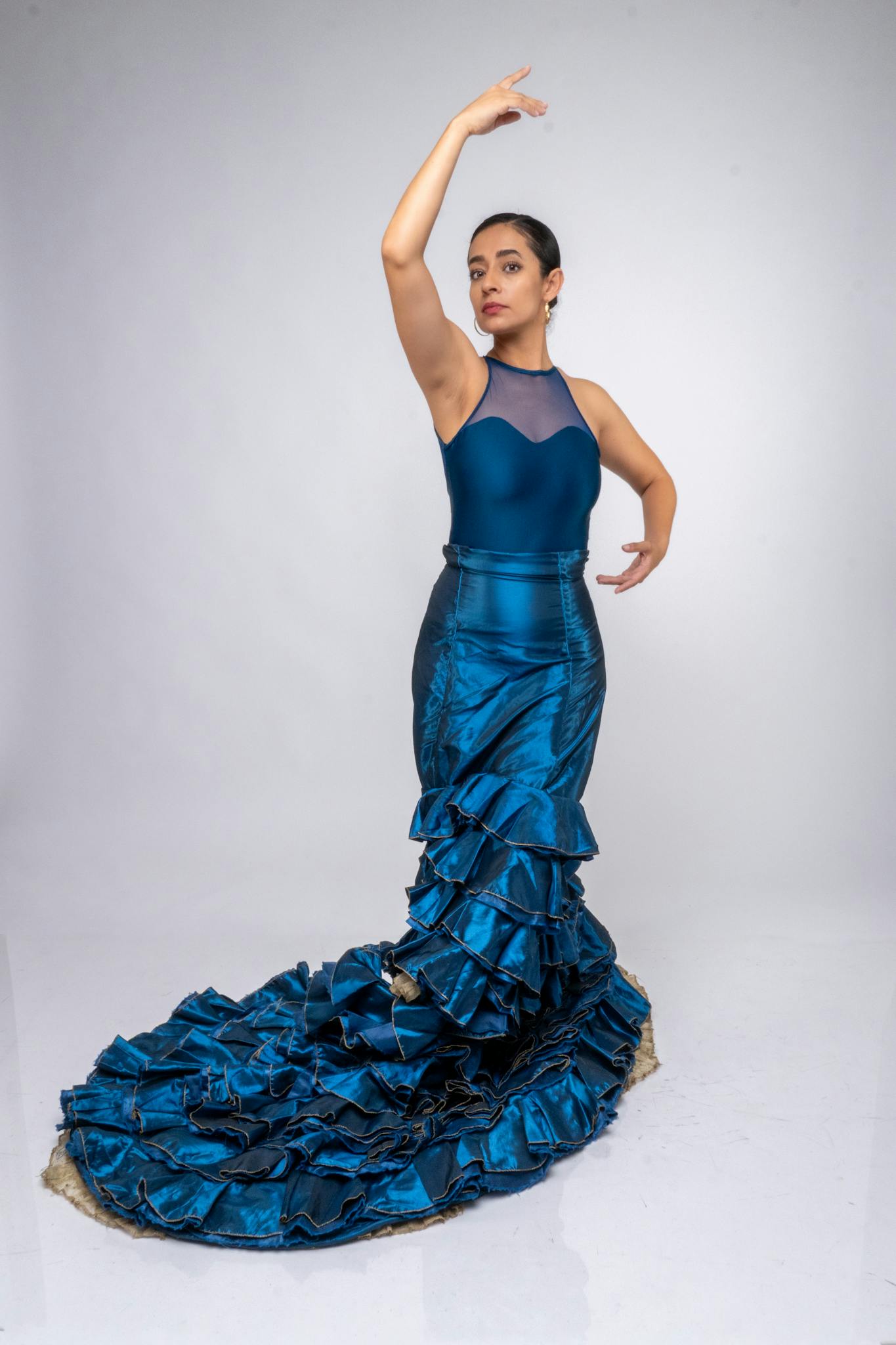 Graceful flamenco dancer posing in a vibrant blue dress, showcasing elegant movements on a clean background.