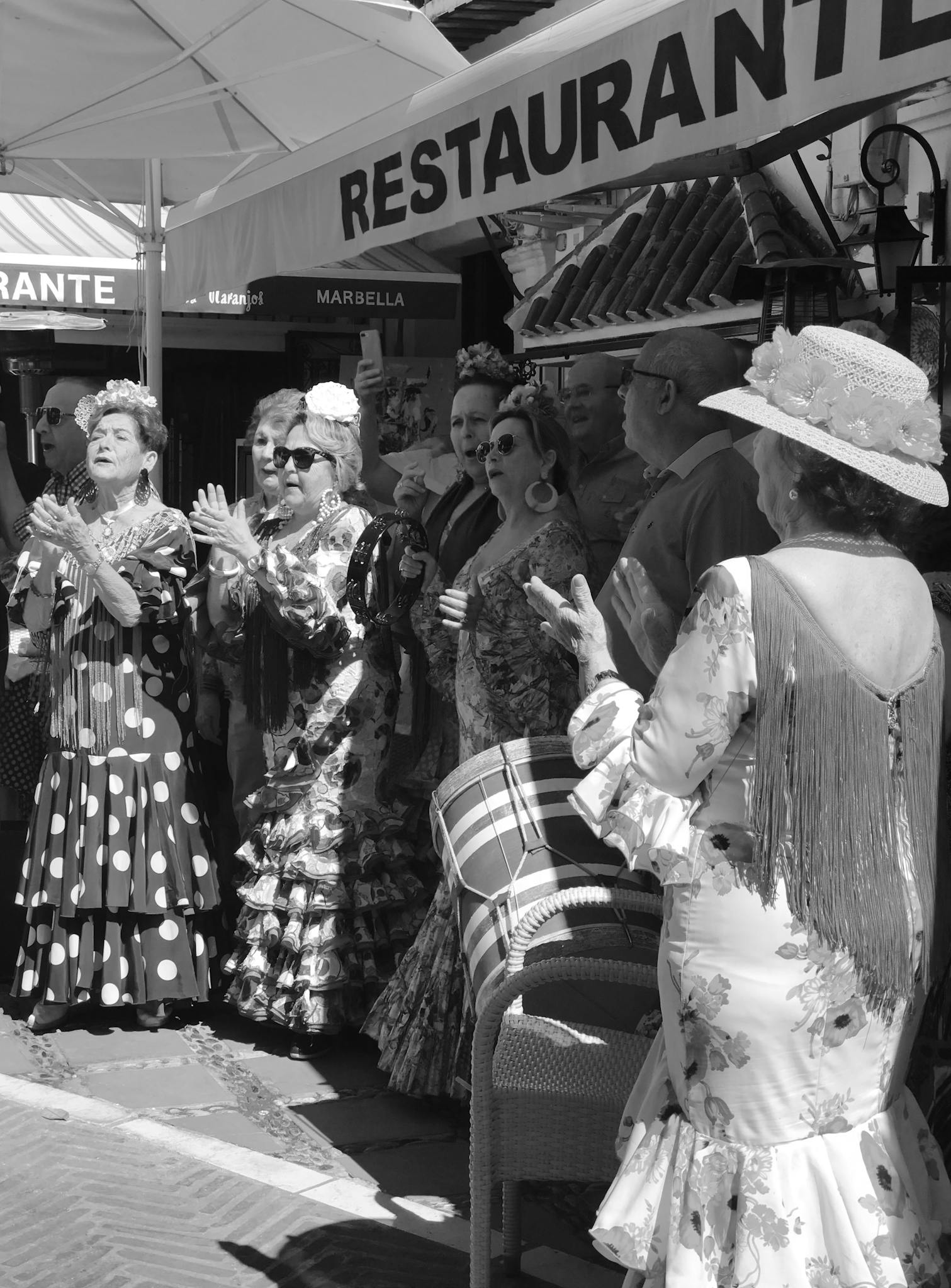 Group of women in traditional flamenco dresses celebrating at an outdoor festival in Spain.